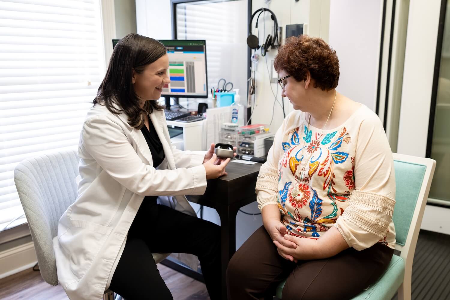 Dr. Huber showing a patient a hearing aid